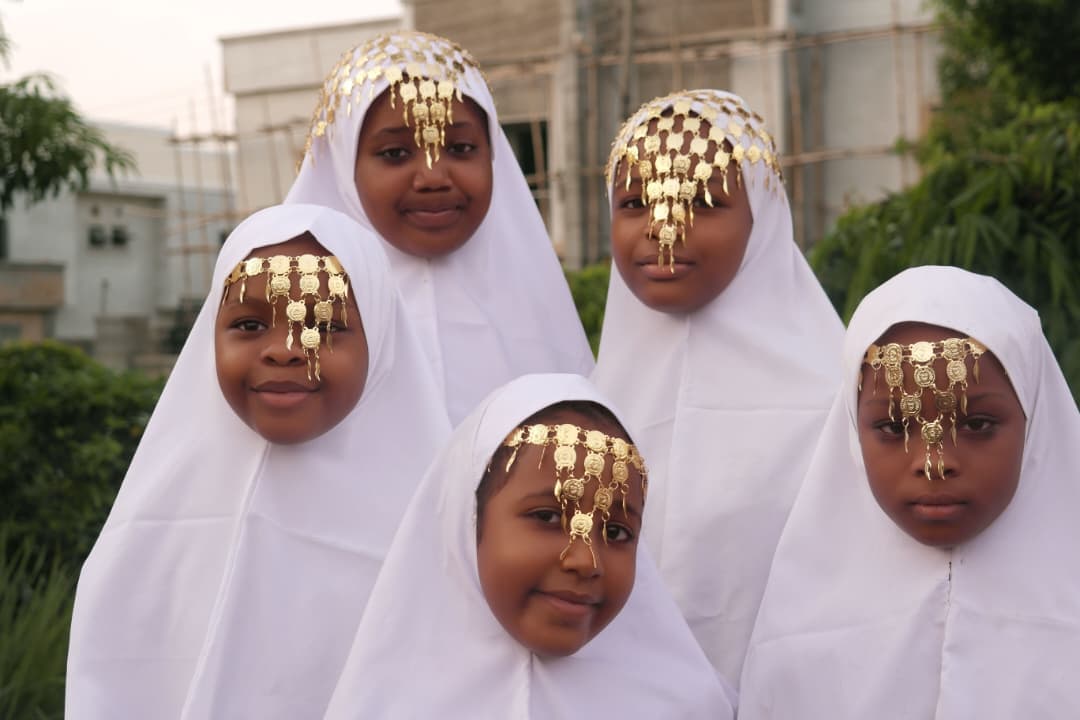 Four girls dressed in white hijab with gold Arabian headpieces